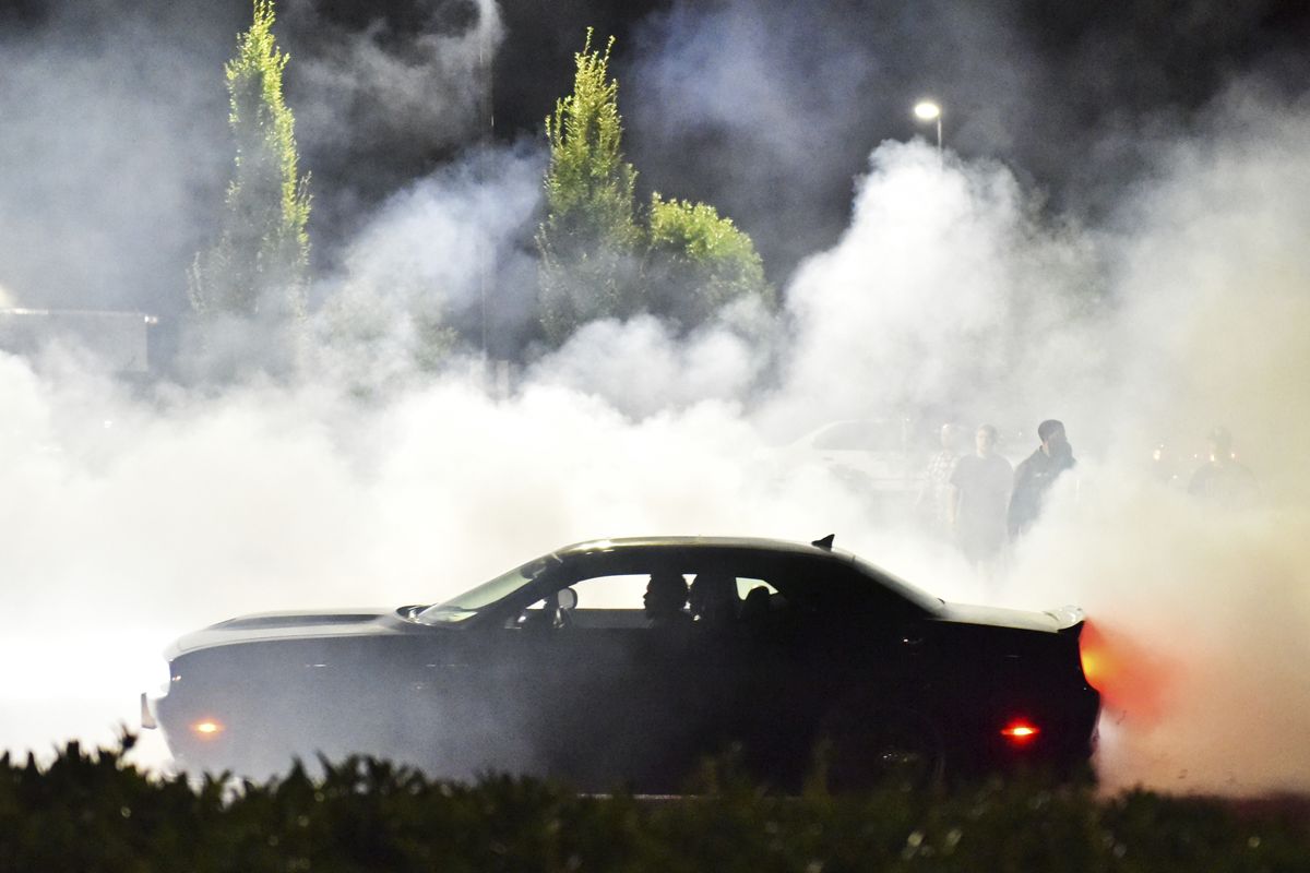 Street racers gather the evening of Sunday, Aug. 12, 2018, in the parking lot of the Goodwill on Northeast Marine Drive and 122nd Avenue in Portland, Ore. Across America, police are confronting illegal drag racing whose popularity has surged since the coronavirus pandemic and lockdowns began. Drivers have blocked off roads to race and to etch donut patterns on pavement with the tires of their souped-up cars. From Portland, Oregon; to Albuquerque, New Mexico; from Nashville, Tennessee; to New York City, officials are reporting a dangerous, and sometimes deadly, uptick in street racing. (Anna Spoerre)