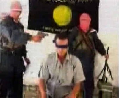 
This image made from television shows a frame from a video posted on an Islamic Web site which  claims to show militants standing over a blindfolded man identified as Turkish hostage Murat Yuce. The man at left, holding a pistol, is seen in later video footage apparently shooting Yuce dead. 
 (Associated Press / The Spokesman-Review)
