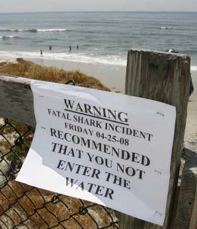 
People play in the water near a sign warning of danger at Cardiff State Beach in Encinitas, Calif., on Friday, after a  shark believed to be a great white killed a swimmer  nearby. Associated Press
 (Associated Press / The Spokesman-Review)