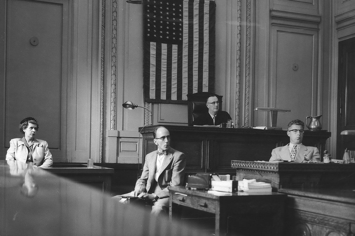 1954: A rare photo taken inside Spokane’s federal court room on the third floor of the federal building at Riverside Avenue and Lincoln Street shows a moment in the civil action brought by Alice M. Revling, left, who sued the U.S. government over a motor vehicle accident with a truck belonging to the Bonneville Power Administration. Also present were court reporter Donald B. Oden, second from left, Judge Sam M. Driver and court clerk Stanley D. Taylor. The courtroom – with high ceilings, ornate vertical trim pieces, called pilasters, marble accents, an oval skylight overhead and heavy wood furnishings – was built when the first federal building and post office was constructed in 1909. Judge Driver rejected Revling’s $72,000 lawsuit against the government.  (SPOKESMAN-REVIEW PHOTO ARCHIVES)