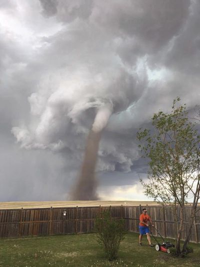 Theunis Wessels mows his lawn Friday, June 2, 2017, at his home in Three Hills, Alberta, as a tornado swirls in the background. Cecilia Wessels, who took the image of her husband to show the tornado to her parents in South Africa, said that the twister wasn't as close it appears. (Cecilia Wessels / Cecilia Wessels/Canadian Press)