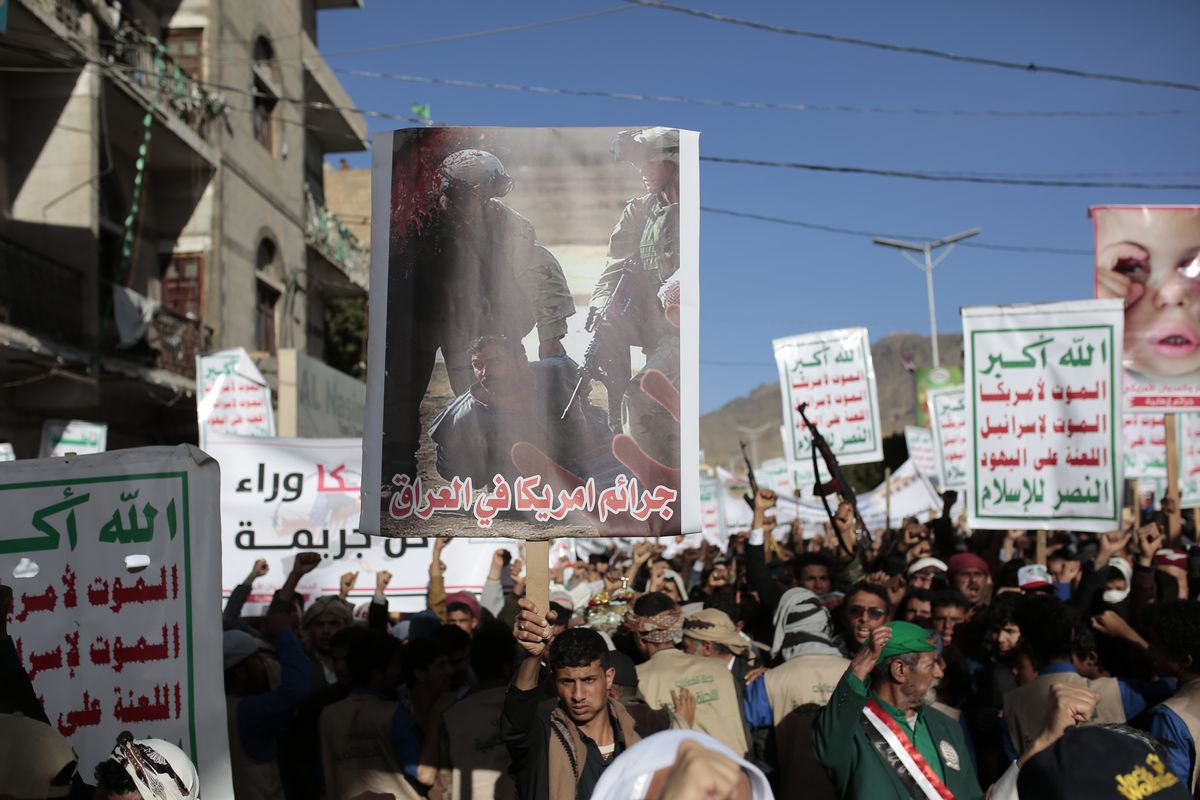 A Houthi supporter holds a poster with Arabic writing that reads "American crimes in Iraq" during a demonstration against the United States over its decision to designate the Houthis a foreign terrorist organization in Sanaa, Yemen, Monday, Jan. 25, 2021.  (Hani Mohammed)