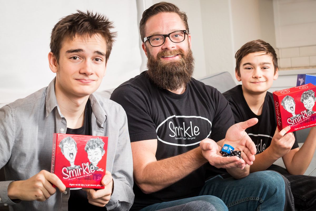 Son Gideon Noble, 16, father Brian Noble and son Gabe Noble, 13, display Smirkle, the first game produced by their new company, NoBull Game Co., a play on their surname, at their home in Veradale on Nov. 30. Smirkle is a dice game inspired by Uno and Farkle.  (Libby Kamrowski/The Spokesman-Review)