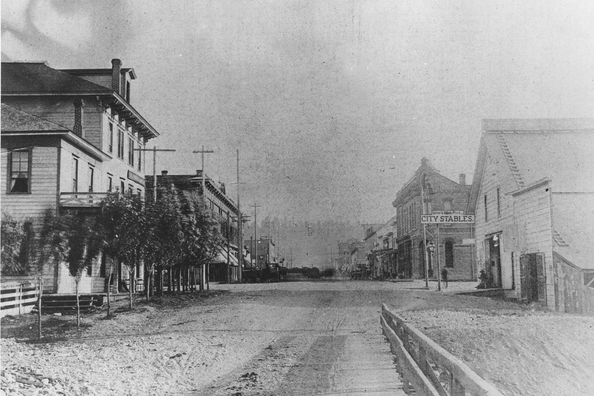 This photo from the mid-1880s shows downtown Spokane from the wooden planks of the Howard Street bridge, built in 1881. To the left is the California House hotel. To the right are the Glover stables, operated by storekeeper and city founder James Glover (Spokesman-Review archives)