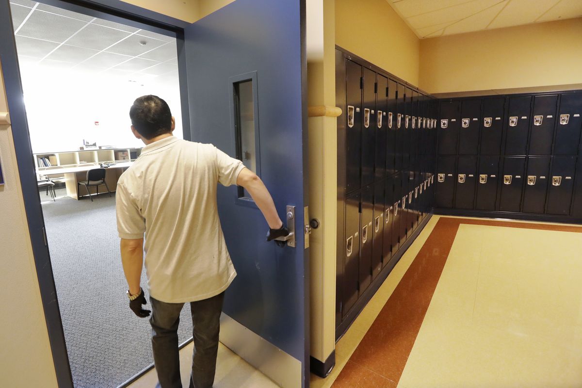 A school janitor opens the door to a staff room inside Bothell High School, closed for the day, Thursday, Feb. 27, 2020, in Bothell, Wash. The suburban Seattle school was closed Feb. 27 after a staffer's family member was placed in quarantine for showing symptoms of possibly contracting the new virus. The school was cleaned and disinfected while students stayed home. On Friday, Oct. 24, the Seattle Public Schools announced the remote learning model would continue for the rest of the current semester because of an increase in COVID-19 cases in King County.  (Elaine Thompson/Associated Press)