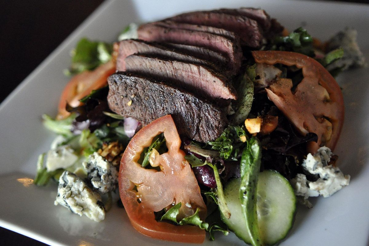 The flat iron steak salad at Elliotts, an Urban Kitchen, features blue cheese, spiced nuts, aged balsamic, cucumber, tomato, greens and pickled onion. (Adriana Janovich / The Spokesman-Review)