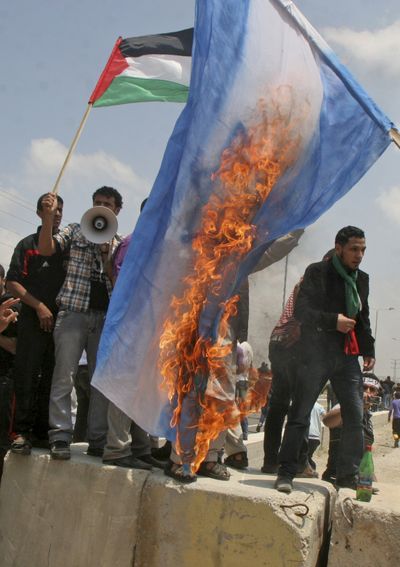 Palestinians burn an Israeli flag during a march heading toward the border with Israel in the northern Gaza Strip on Sunday. (Associated Press)
