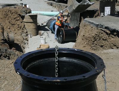 Brent Imholt, of the Spokane Water Department construction crew, attaches a chain to a 30-inch water main tee on Friday. Crews are working at the corner of 37th Avenue and Stone Street on a three-month project to replace the old pipes, which waste water through leaks.  (Dan Pelle / The Spokesman-Review)