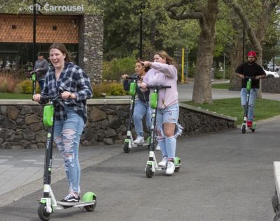 Teens ride Lime scooters around Riverfront Park on Friday. The scooters are a popular way for teens to pass the time in the park with their friends.  (Jesse Tinsley/THE SPOKESMAN-REVIEW)