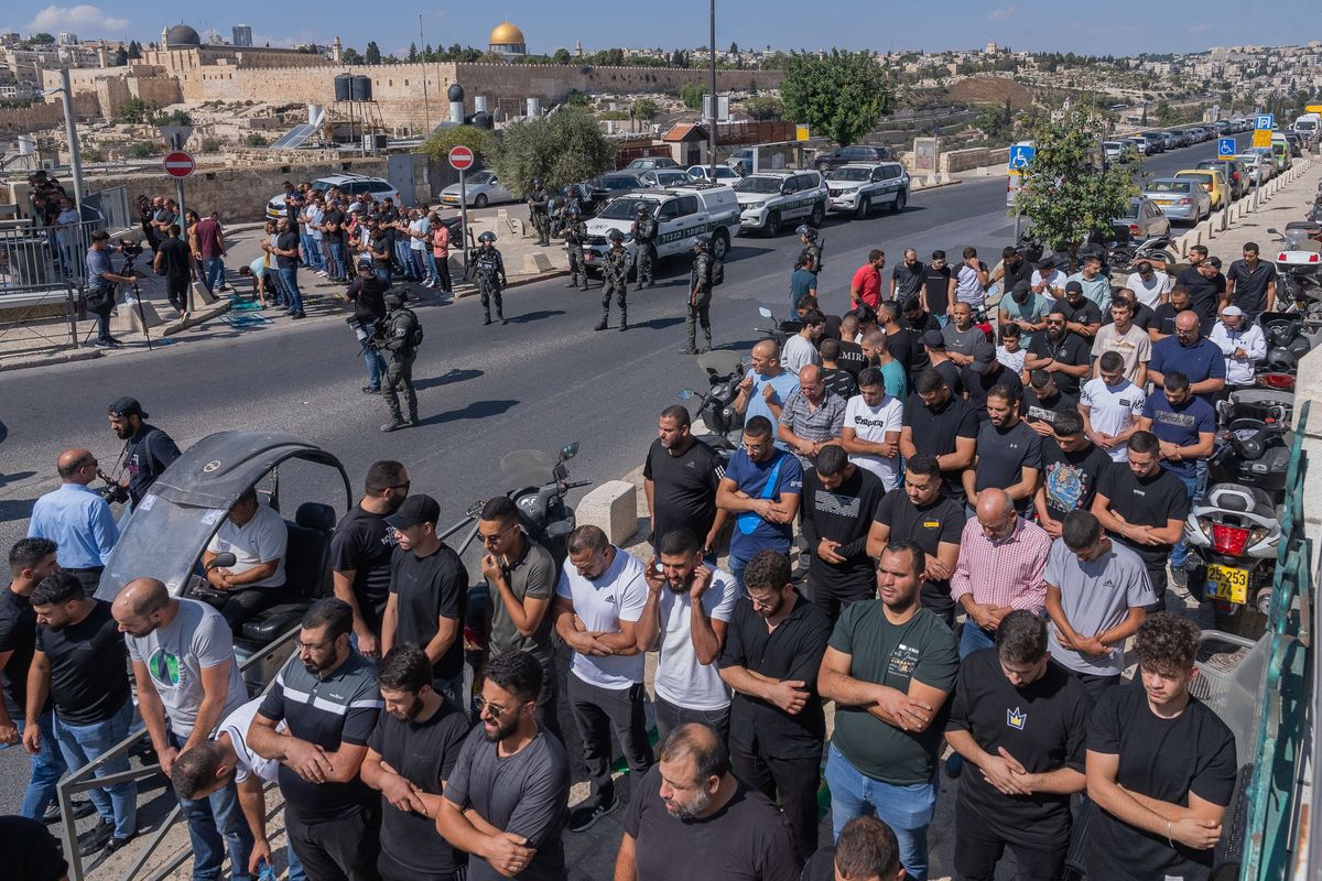 Muslim men perform Friday prayers on the side of a street in Jerusalem as Israeli security forces block the road leading to the al-Aqsa Mosque, the golden dome of which can be seen on the horizon, on Friday. Police officers allowed only about 5,000 elders to attend Friday prayers at the mosque, one of the holiest sites in Islam, according to the Waqf, the authority in charge of the site.   (New York Times)
