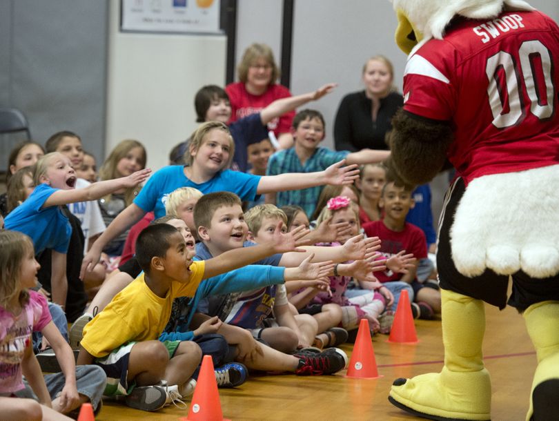 Broadway Elementary School students extend hands for high-fives from from Swoop, the Eastern Washington University mascot during an assembly, May 17 in the school gym. (Dan Pelle)