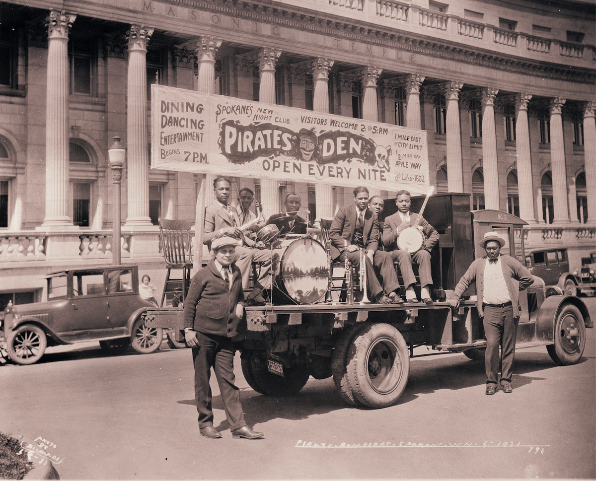To advertise the Pirate’s Den, later called the Harlem Club, a truck carried band members and banners through downtown Spokane. Photographer W. Richards snapped this 1931 image in front of the Masonic Temple on Riverside Avenue. Club owner E.J. Brown stands at right; musician Buck Pierce Campbell sits on the truck bed, 3rd from right.  (Eastern Washington State Historical Society/Northwest Museum of Arts and Culture)