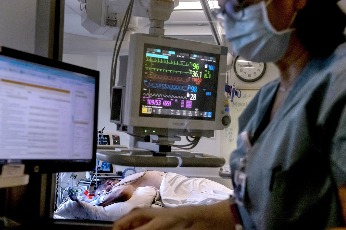 Nurse Julie Mathews updates the chart of COVID-19 patient Ralph Bye in the ICU at Providence Sacred Heart Medical Center on Wednesday, Dec. 16, 2020.  (Kathy Plonka/The Spokesman-Review)