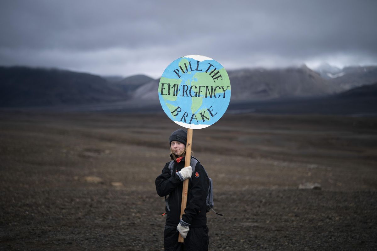 A girl holds a sign that reads ‘pull the emergency brake’ as she attends a ceremony in the area which once was the Okjokull glacier, in Iceland, Sunday, Aug. 18, 2019. With poetry, moments of silence and political speeches about the urgent need to fight climate change, Icelandic officials, activists and others bade goodbye to the first Icelandic glacier to disappear. (Felipe Dana / AP)