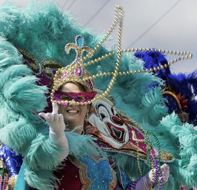This file photo shows a masked rider throwing beads during the Krewe of Iris Mardi Gras parade in New Orleans.  (Associated Press / The Spokesman-Review)