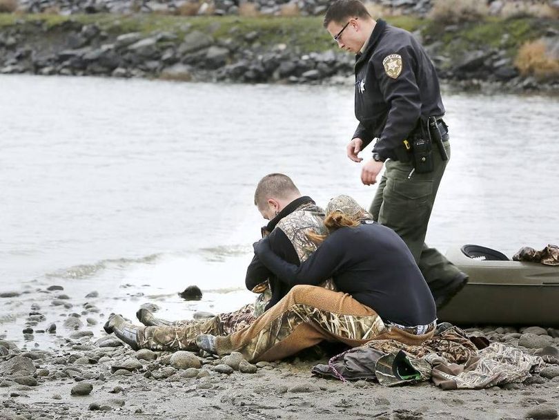 Melody Priest wraps herself around her husband, Justin, to warm him before medical personnel arrive to treat him after he fell into the Columbia River trying to retrieve a duck near Finley.  (Bob Brawdy / Tri-City Herald)
