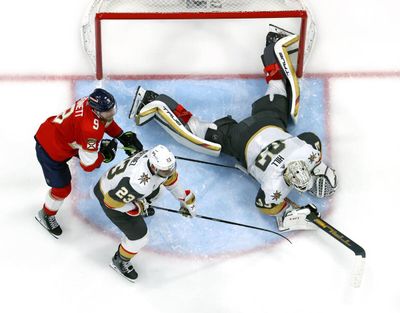 Golden Knights goaltender Adin Hill dives for a puck with teammate Alec Martinez and Florida Panthers center Sam Bennett nearby during Game 3 on Thursday in Sunrise, Fla.  (Tribune News Service)