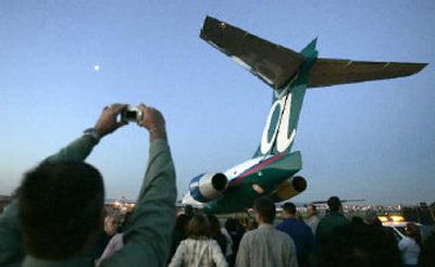 
An employee takes a picture as the last Boeing 717 to be built in California is towed to the flight ramp at Long Beach Airport. 
 (Associated Press photos / The Spokesman-Review)