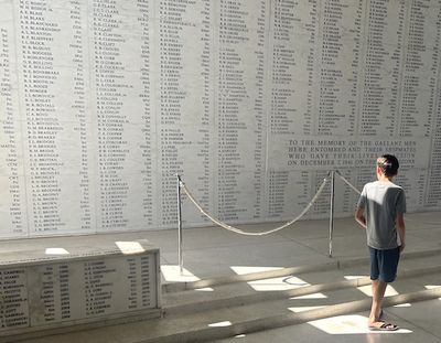 A young visitor stands in front of the wall bearing the names of those who died on the USS Arizona. (Dan Webster)