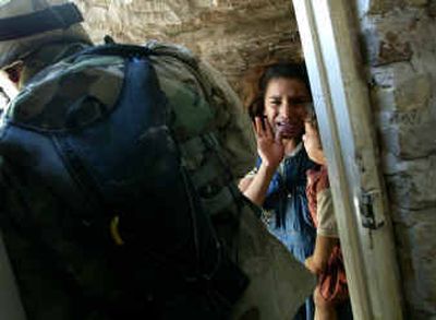 An Iraqi girl cries while holding her younger sibling as U.S. soldiers conducting searches kick down a door and enter a house in Baghdad on Wednesday.
(Associated Press / The Spokesman-Review)
