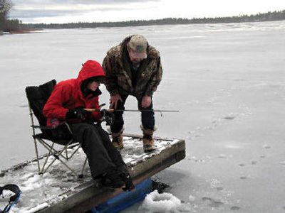 
Tom Fisher of the Inland Northwest Wildlife Council gives a few pointers to Michelle Moss, a junior at Ferris High School, as she tries ice fishing off the dock at Jerry's Landing on Eloika Lake. 
 (The Spokesman-Review)