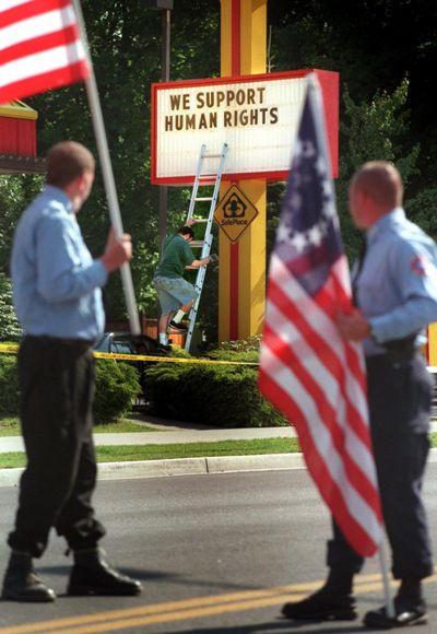 In this 1999 file photo, Aryan Nations marchers as watch John Mattmiller, who cooks at Zips on Sherman Ave., finishes posting the marquee message on the sign in front of the restaurant before the parade. (File photo/SR)