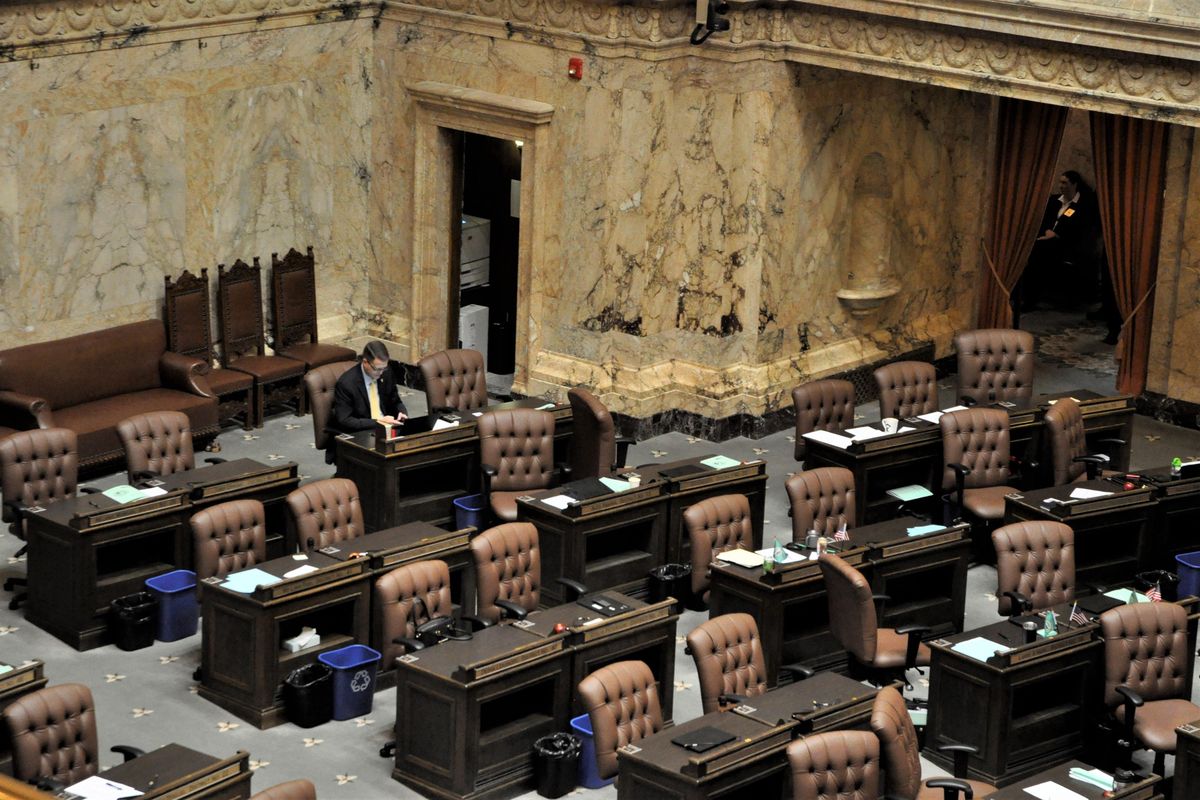 Rep. Matt Shea sits at his desk in an empty House chamber last week while Republican and Democrats met in their caucus rooms. Shea’s floor seat was moved from the middle of GOP House members to the last row after he was kicked out of the Republican caucus. (Jim Camden / The Spokesman-Review)
