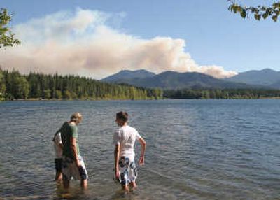
Sarah Root,  Kaelan Nelson and Steven Root, from left, stand in Kachees Lake near Easton, Wash., as smoke fills the skyline Thursday. The fire was sparked when a helicopter carrying four people crashed Thursday. Associated Press
 (Associated Press / The Spokesman-Review)