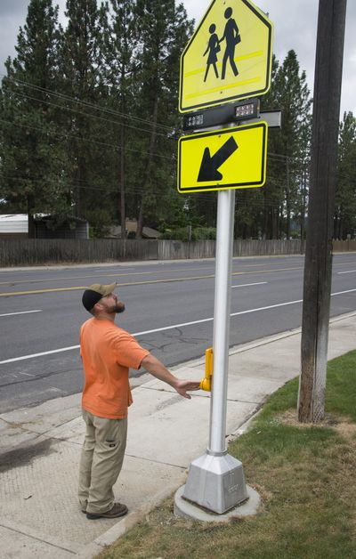 Tyler Nelson, with the Spokane County Signal Shop, tests recently installed crosswalk flashing lights Tuesday in front of Mead High School on Hastings Road. (Colin Mulvany / The Spokesman-Review)