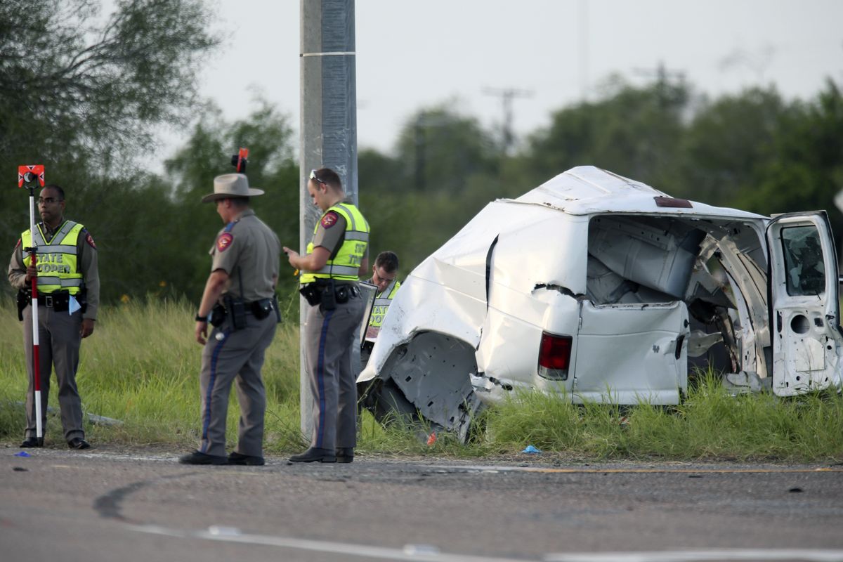 Texas Department of Public Safety officers stand near a vehicle where multiple people died after the van carrying migrants tipped over just south of the Brooks County community of Encino on Wednesday, Aug. 4, 2021, in Encino, Texas. The van crashed against a utility pole after it attempted to turn off of Highway 281 onto Business 281. Encino is about 2 miles (3.22 kilometers) south of the Falfurrias Border Patrol checkpoint. (Delcia Lopez)