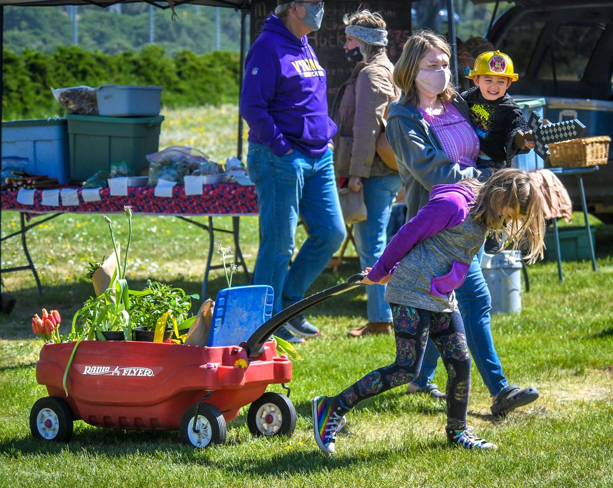 Isla Hartsell, 8, hauls a wagon full of items for Kat Hartsell and Theo Cruz, 2, on the first day of the Spokane Farmers Market on May 8, 2021, at the corner of Fifth Avenue and Browne Street. The wagon contained tulips, tomato, herbs and pea plants.  (Spokesman-Review photo archives)