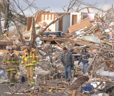 Firefighters survey Devonshire Street in Washington, Ill., on Sunday. Intense thunderstorms and tornadoes swept across the Midwest, causing extensive damage in several central Illinois communities while sending people to their basements for shelter. (Associated Press)