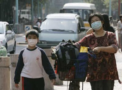 
A  student and his mother, wearing masks as a preventive measure against a  flu outbreak, leave a primary school  Wednesday. Hong Kong has asked a  scientist to study the deaths of three children. Associated Press
 (Associated Press / The Spokesman-Review)