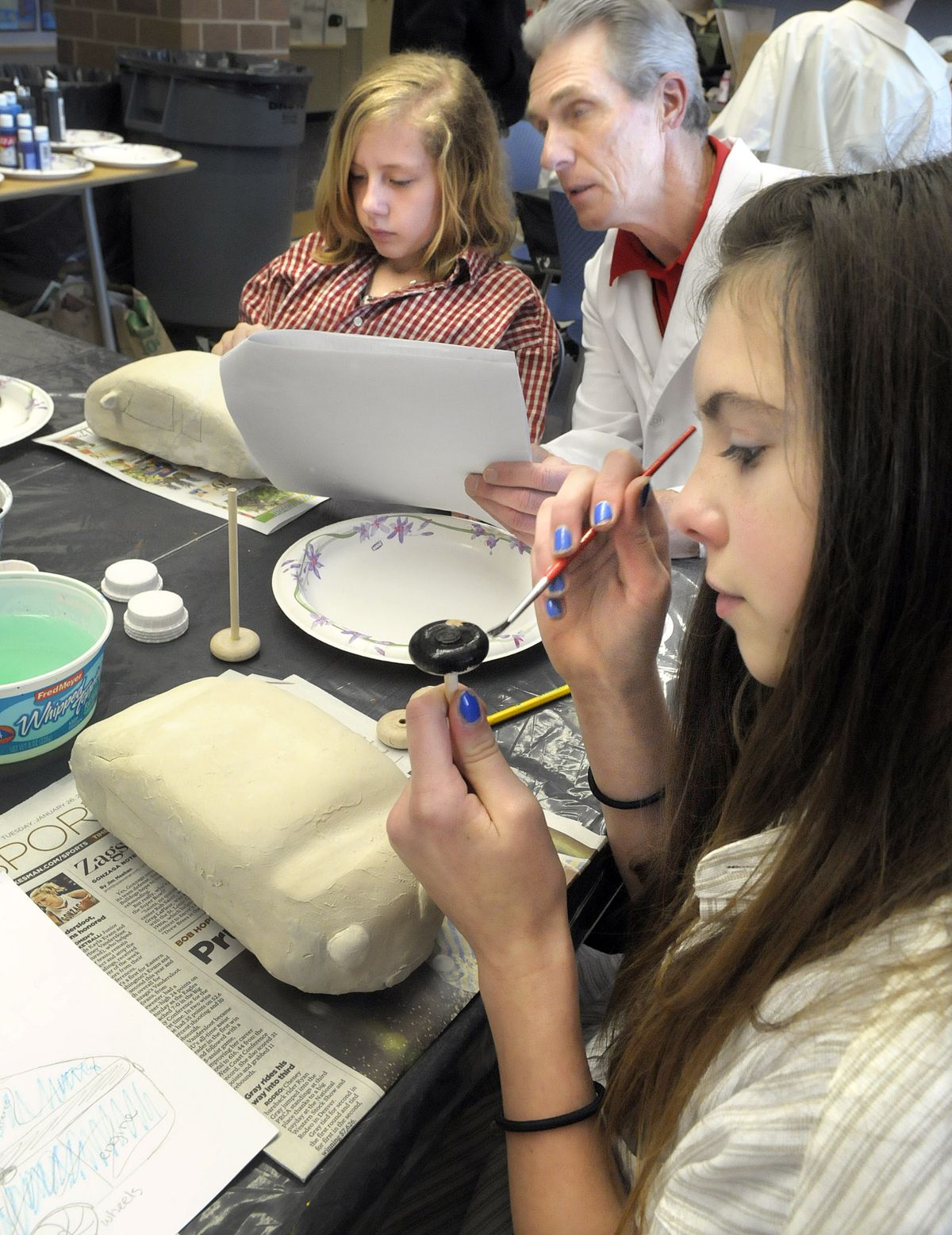 Olivia Delger, left, and Ruby Camp, right, put the finishing touches on their cars. They worked with retired NASA engineer Tom Crocker, center, to design and build the cars. (CHRISTOPHER ANDERSON)