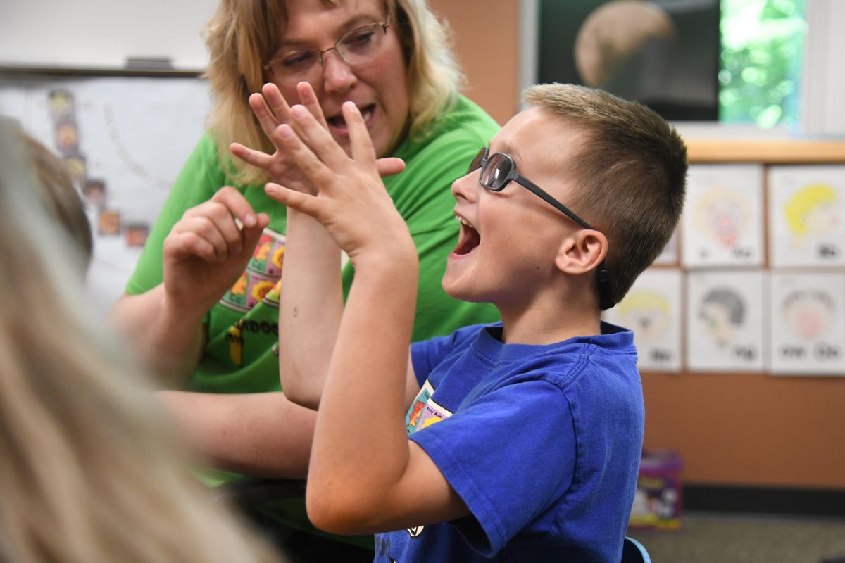 Blake Barnett exuberantly asks for and arts and craft “eye” piece so he can complete a man-on-the-moon face art project, June 26, 2019, during his stay at Camp Candoo WSU Department of Speech and Hearing Clinic. WSU graduate student Jennifer Westby-Klassen works with Blake. The children were encouraged to ask for every item while building the projects. (Dan Pelle / The Spokesman-Review)