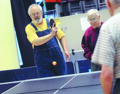 Ernie Buckler serves  to Don Dinsmore as Al McKimmey watches on June 15. The senior  pingpong group was kicked out of the Spokane Valley Senior Center weeks ago and has  since relocated to the Hepton Point Community Center in the Valley Real Life Church. (J. BART RAYNIAK)
