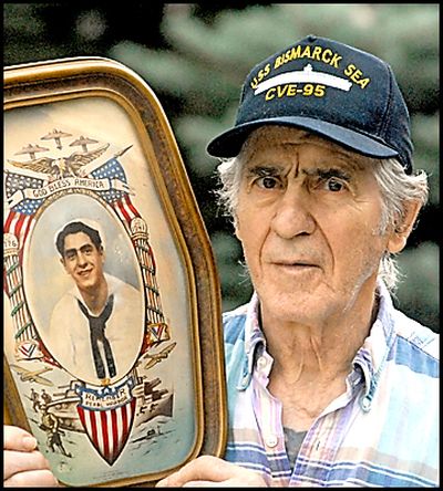 Ernest Peluso holds a colorized photograph of himself taken just before he got out of the Navy in 1945. The WWII veteran survived the sinking of the aircraft carrier USS Bismark Sea off Iwo Jima and was in the water all night until he got picked up by a destroyer.  J. BART RAYNIAK The Spoksman-Review (J. Rayniak / The Spokesman Review)