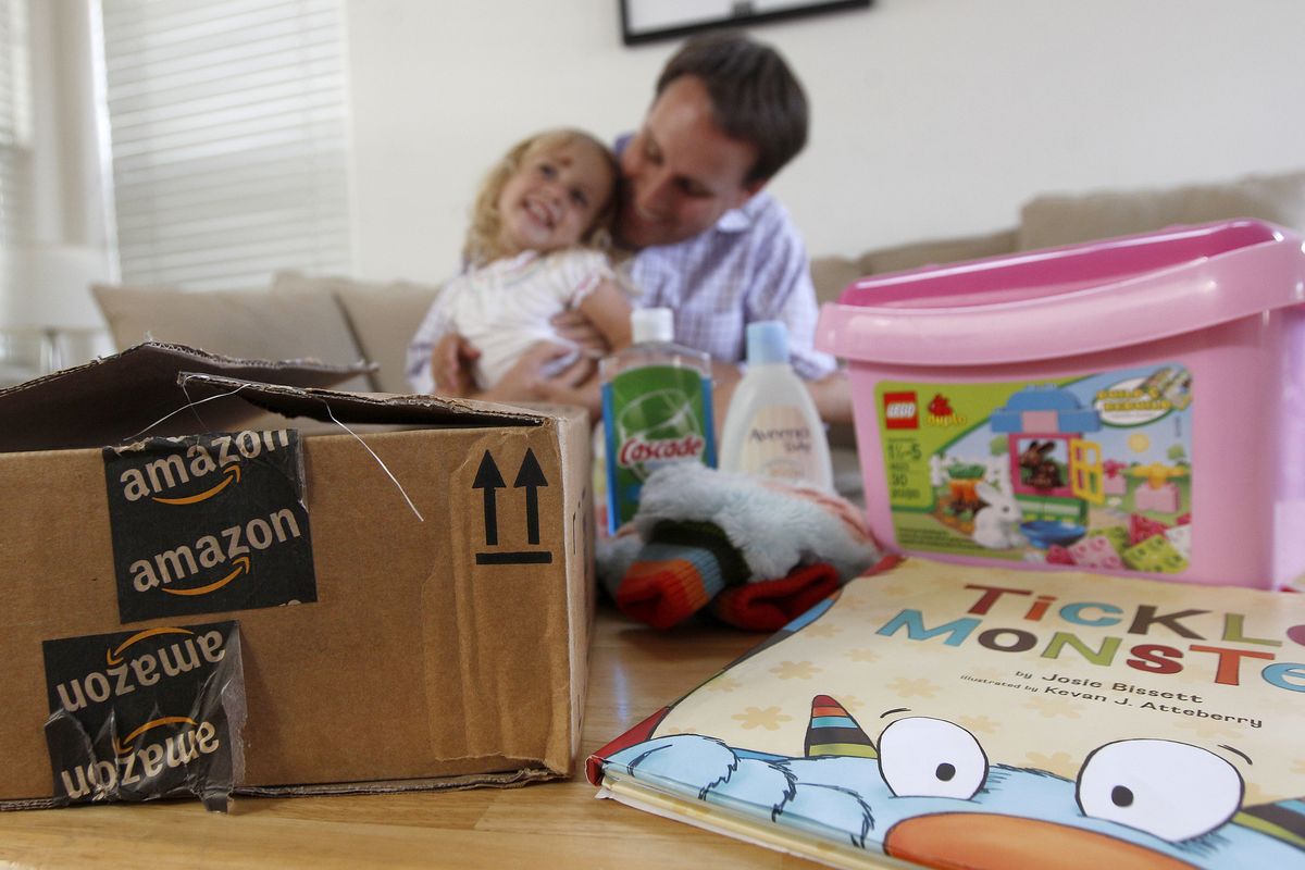 Reid Butler plays with his daughter Siena, 2, as they pose for photographs with recent online purchases from Amazon at their home in Walnut Creek, Calif., Thursday, Sept. 13, 2012. Products are flying off the shelves at Amazon warehouses across the county as Californians prepare to start paying sales taxes on online purchases. (Jeff Chiu / Associated Press)