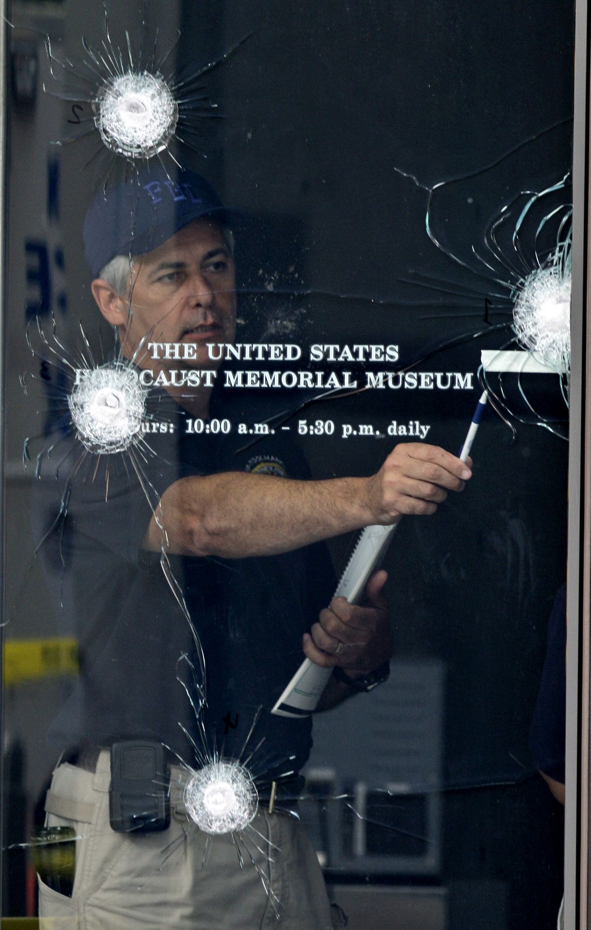 An FBI investigator examines bullet strikes in one of the doors of the U.S. Holocaust Memorial Museum in Washington on Thursday.  (Associated Press / The Spokesman-Review)