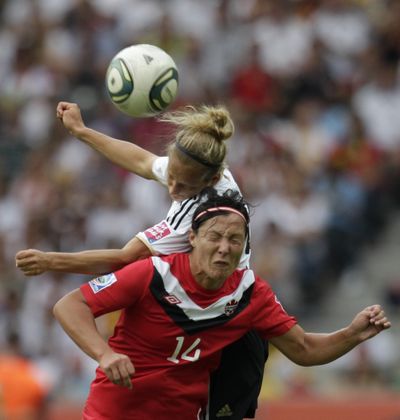 Germany's Babett Peter, back, and Canada's Melissa Tancredi challenge for the ball during the Group A match. (Associated Press)