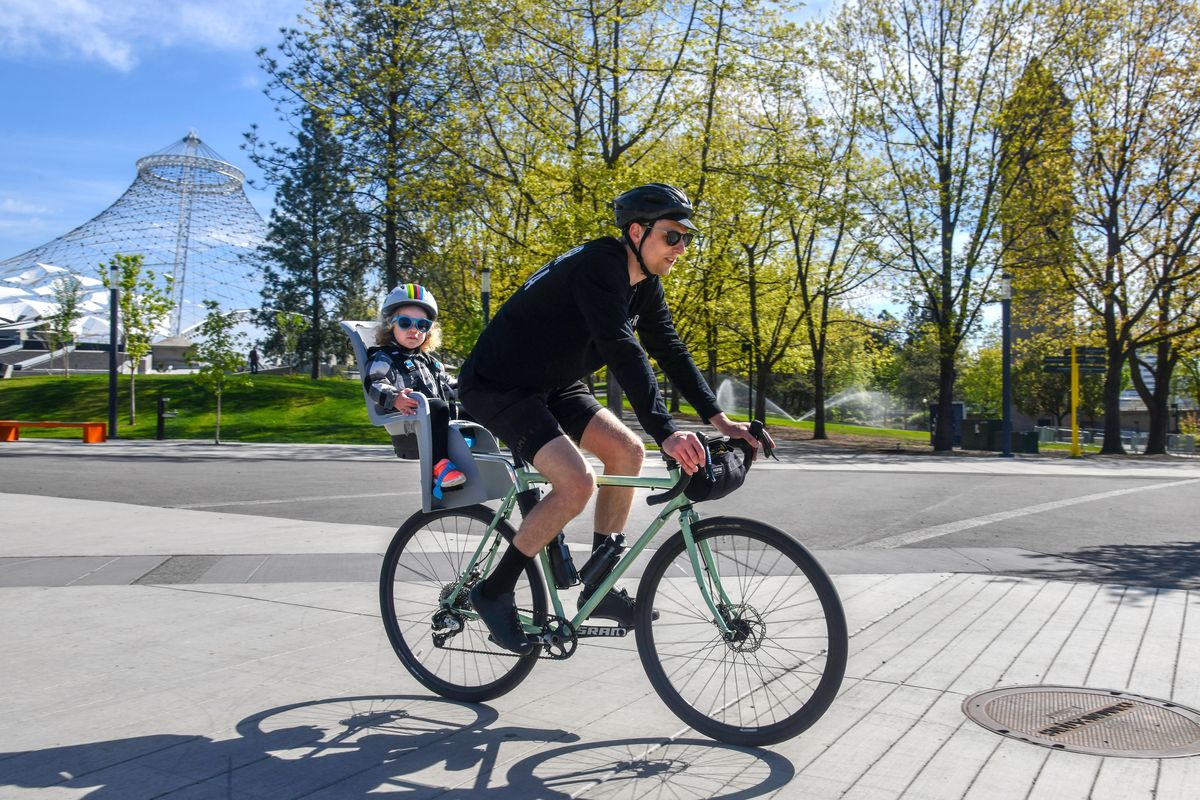 Joseph Peterson and his daughter Ivy, 2, saw their shadows on a brilliant Wednesday morning bike ride, May 5, 2021, in Riverfront Park.  (Dan Pelle/THE SPOKESMAN-REVIEW)