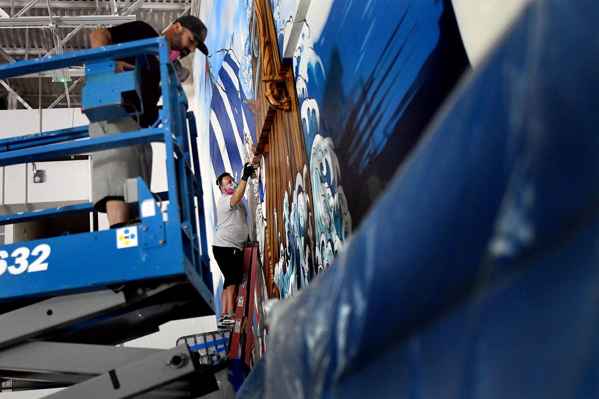 Jeremy Deming, foreground, and Scott Lakey work on a mural in the gym at Coeur d’Alene High School on June 24.  (Kathy Plonka/The Spokesman-Review)
