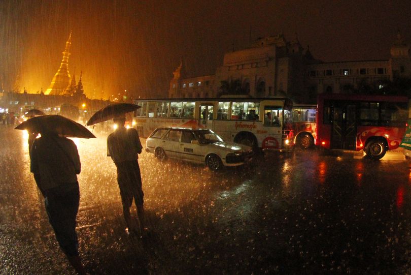 Pedestrians make their way along a flooded road while vehicles make slow progress in heavy traffic on Thursday, Aug 22, 2013, in Yangon, Myanmar. Heavy rains on Thursday evening caused road flooding and traffic congestion in many parts of Yangon. (Khin Win / Associated Press)