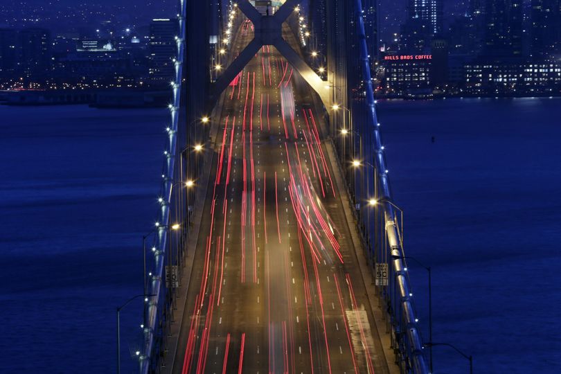 In this Sept. 3, 2014, picture made with a long exposure, lights from evening rush hour traffic move over the San Francisco Oakland Bay Bridge in San Francisco. (Marcio Sanchez / Associated Press)