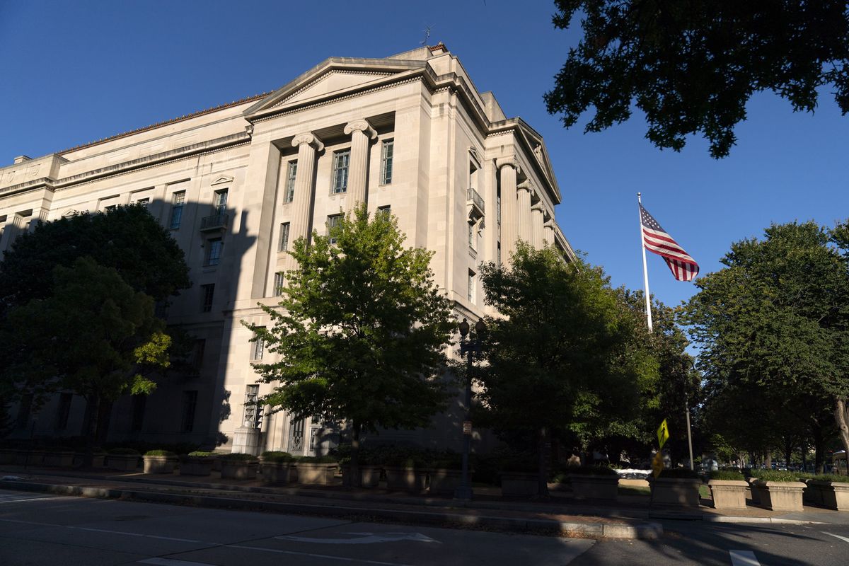 This Oct. 8, 2020 photo shows an American flag flies outside of the Justice Department building in Washington. The elite Russian hackers who gained access to computer systems of federal agencies last year didn’t bother trying to break one-by-one into the networks of each department. Instead, they got inside by sneaking malicious code into a software update pushed out to thousands of government agencies and private companies.  (Jacquelyn Martin)