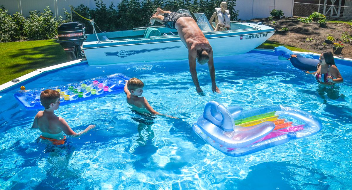 Tim Lorentz dives from his “LaFloata” boat fitted to his above-ground swimming pool during an afternoon splash Monday in Spokane. Neighbors, Ryan, left, and Zachary Schwartz along with Allie Lorentz, right, cool off as a heat wave hits. (DAN PELLE/THE SPOKESMAN-REVIEW)