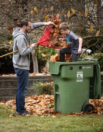 While raking their front yard, Luke Goshorn, 6, helps his father Ross stomp down the sycamore leaves in the collection bin Nov. 2, 2018, on Spokane’s South Hill. (Colin Mulvany / The Spokesman-Review)