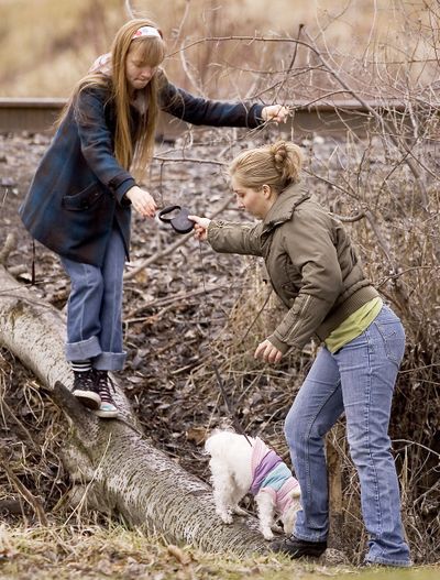 Stacie Flores, left, 15, of Lewiston, Idaho, passes the leash for Polly, a 2-year-old Maltese, to her sister Kathleen, 20, as she crosses a log over a full ditch near Reaney Park on Thursday, Feb. 11, 2010, in Pullman, Wash. The Flores took advantage of the unseasonably mild weather to walk their dogs, including Frannie, not seen, an 8-year-old mix breed, while they waited for their mother to finish work, and before starting a dance class. (Dean Hare / Moscow-pullman Daily News)