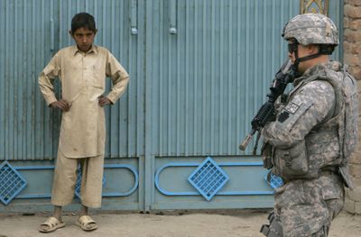 An Afghan boy looks on as a U.S. soldier patrols near the Pakistani border in  eastern Afghanistan on Tuesday.  (Associated Press / The Spokesman-Review)