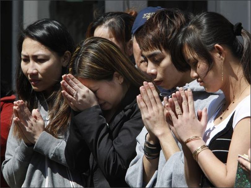 Tina Nguyen, second from left, prays with relatives of shooting victims Lan Ho and Long Huynh outside the American Civic Association in Binghamton, N.Y. Jiverly Wong killed 13 people in a shooting rampage at the immigrant community center on Friday. (AP Photo/Matt Rourke) (April 05, 2009) (The Spokesman-Review)